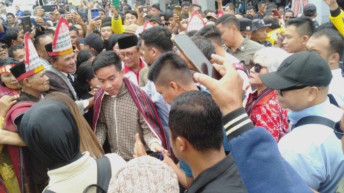 Cawapres Gibran Rakabuming diulosi masyarakat sekitar saat tiba di Bandara Silangit, Sabtu (18/11/2023). 