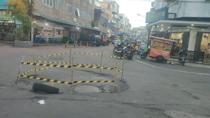 Kondisi jalan  yang nyaris amblas yang sudah dipagari usai viral di sosial media, Minggu (3/11/2024). Akibat jalan yang nyaris amblas ini pedagang sate padang ini alami penurunan omzet yang signifikan.