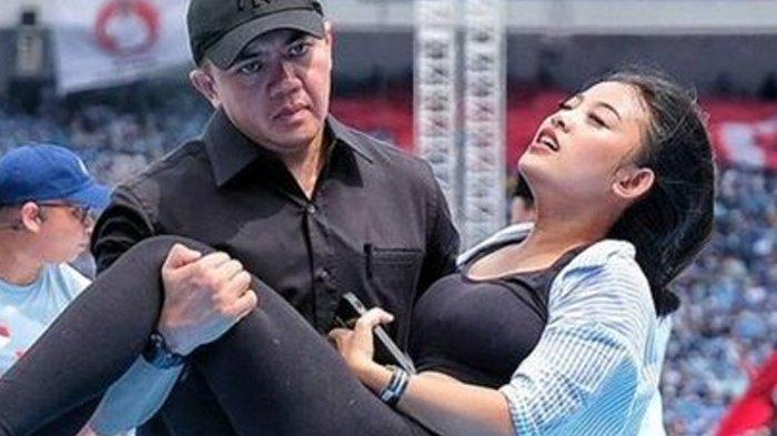 WANITA PINGSANG - Capres 02 Prabowo Subianto (kanan) berpidato saat seorang perempuan sedang pingsang dibopong Mayor Teddy dari atas panggung saat kampanye di Stadion Gelora Bung Karno di Jakarta pada 10 Februari 2024. (Yasuyoshi CHIBA/AFP)