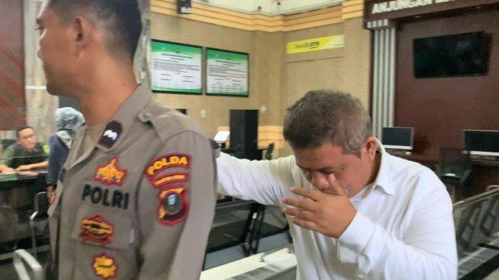 Mantan anggota DPRD Labuhanbatu, Rudi Syahputra, berusaha menutup wajahnya di depan kamera usai menjalani sidang di ruang Cakra II, Pengadilan Negeri Medan, Rabu (4/9/2024).