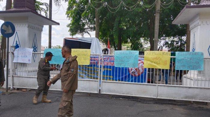 Massa yang merupakan warga Desa Buntu Bedimbar Kecamatan Tanjung Morawa Kabupaten Deli Serdang membentangkan poster di depan pintu gerbang keluar kantor Bupati saat melakukan aksi Senin, (3/6/2024). 