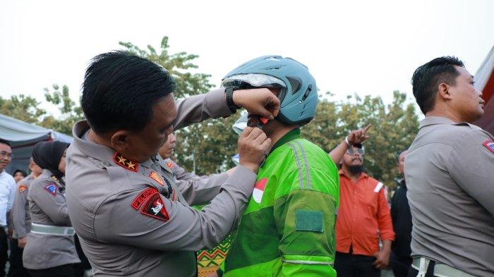 Kapolda Sumut Irjen Pol Panca Putra Simanjuntak memasangkan helem kepada Penarik Ojol sebagai tanda pelopor keselamatan sela-sela dengar Curhatan Pengendara Ojol dan Parbetor di Medan, Jumat (23/6/2023)