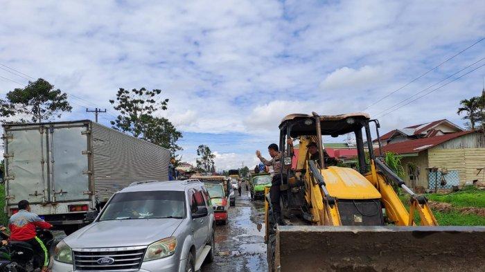 Personel Polres Tanah Karo melakukan pembersihan dan penimbunan jalan provinsi yang rusak di Jalan Jamin Ginting, tepatnya di Desa Raya, Berastagi, Kamis (13/7/2023)
