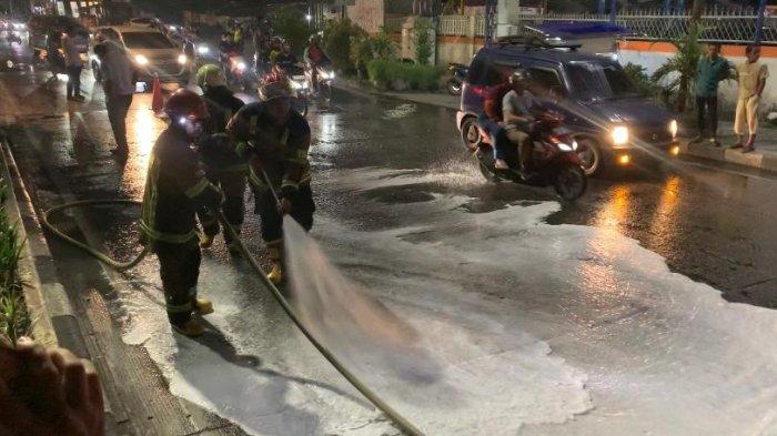 Petugas Damkar tampak sedang menyiram tumpahan minyak yang sebabkan belasan pengendara tergelincir, Selasa (1/8/2023). 
 