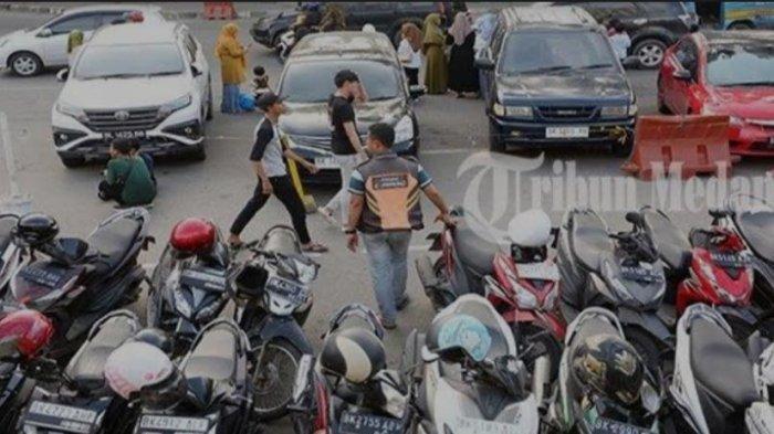 Petugas parkir meminta retribusi parkir kepada pengendara roda dua di depan Stasiun Kereta Api Medan Jalan Kereta Api, Kota Medan, Rabu (3/1). Dinas Perhubungan Kota Medan akan memberikan stiker  parkir berlangganan kepada pengendara dalam waktu dekat.  (TRIBUN MEDAN/ABDAN SYAKURO)
