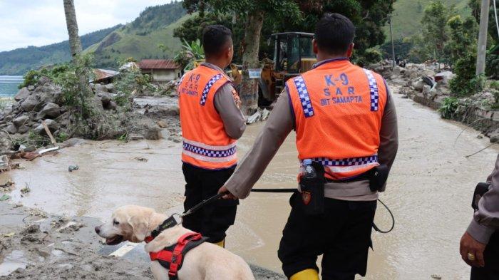 Personel Polda Sumut menmbawa anjin pelacak saat mencari 11 warga yang hilang akibat bencana alam tanah longsor yang terjadi di Dusun III, Desa Simangulampe, Kecamatan Bakti Raja, Kabupaten Humbang Hasundutan (Humbahas), Minggu (3/12/2023)