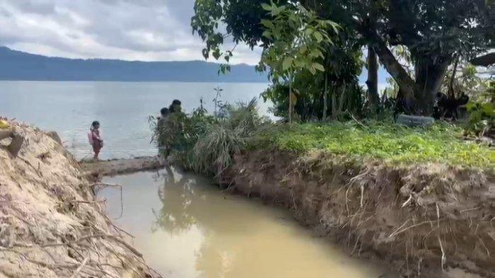 RUMAH TERISOLASI: Tangis pilu satu keluarga di tepi Danau Toba, di sekeliling rumahnya dikeruk orang lain yang diduga lebih memiliki kemampuan materi. Peristiwa di luar kemanusiaan ini terjadi ini Desa Unjur, Kecamatan Simanindo, Kabupaten Samosir, Sumatera Utara, Senin (21/1/2025). Rumah itu ditempati keluarga Darma Ambarita dan istrinya Rentina Sihotang. Tampak Danau Toba sudah menggenangi sekeliling rumahnya. (HO/SINTA SIHOTANG)