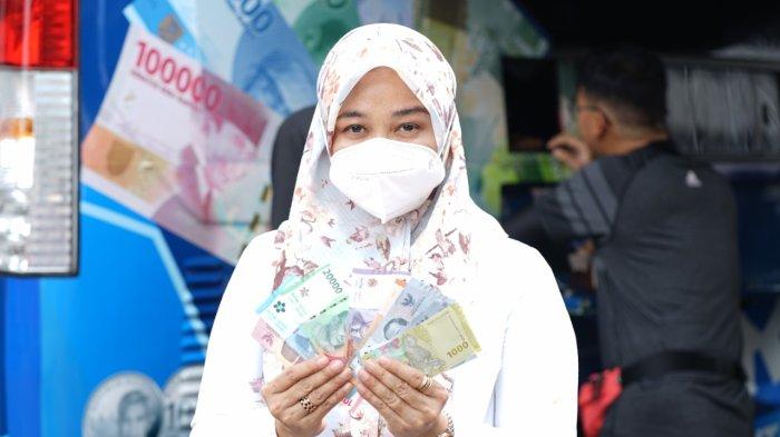 Salah seorang warga menunjukkan uang baru di acara Car Free Day (CFD) Pekan QRIS Nasional (PQN) 2022, di kawasan Lapangan Merdeka, Kota Medan, Minggu (21/8/2022).