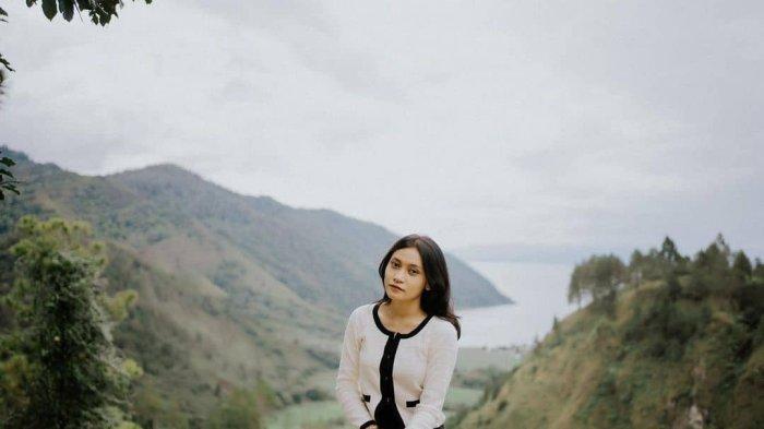 Seorang warga berpose dengan latarbelakang pemandangan alam Danau Toba di Adian Nalombok Jalan Lintas Sumatera Nomor 126, Gurgur Aek Raja, Kecamatan Tampahan, Toba, Sumatera Utara, beberapa waktu lalu.