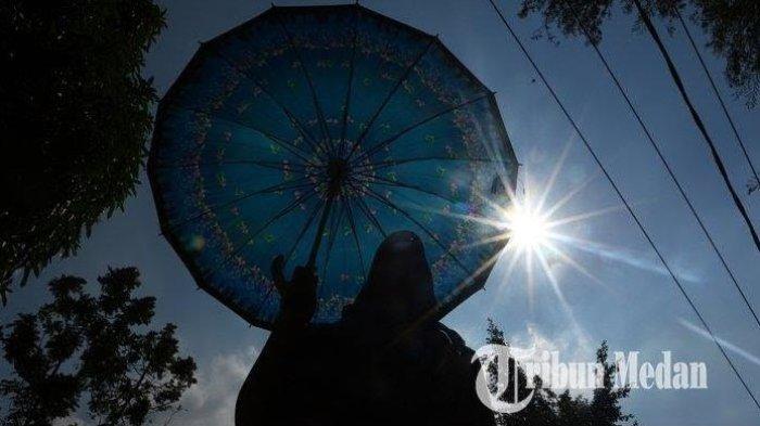 ILUSTRASI - Warga menggunakan payung untuk menghindari teriknya panas matahari di Jalan Agus Salim, Kota Medan.