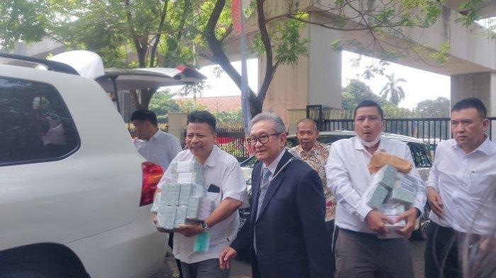 Pengacara terdakwa Irwan Hermawan, Maqdir Ismail membawa tumpukan dolar Amerika Serikat ke Kejaksaan Agung, Kamis (13/7/2023). Tumpukan dolar yang dibungkus plastik bening itu mencapai USD 1,8 juta. Jika dirupiahkan, nilainya mencapai Rp 27 miliar.