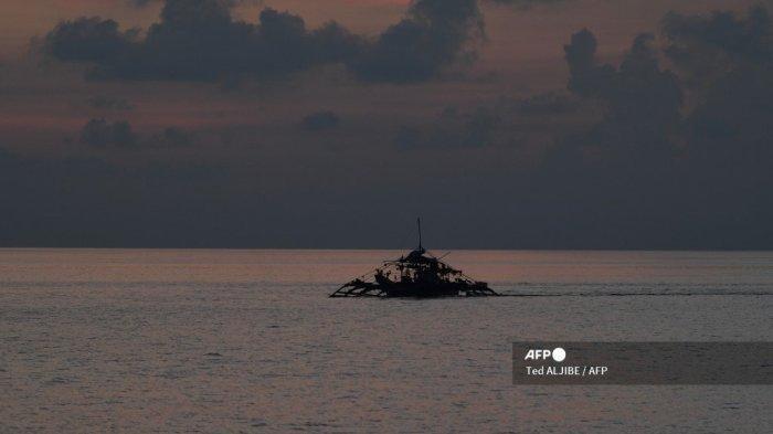 Dalam foto yang diambil pada tanggal 21 September 2023 ini, sebuah kapal nelayan Filipina sedang berlabuh saat matahari terbenam di dekat Scarborough Shoal yang dikuasai Tiongkok di Laut Cina Selatan yang disengketakan. Filipina menuduh Tiongkok memasang 'penghalang mengambang' untuk menghentikan kapal penangkap ikan memasuki wilayah sengketa di Laut Cina Selatan.