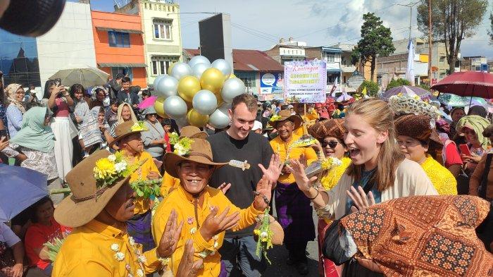 Dua orang wisatawan mancanegara asal dari Kota Sheffield, Inggris, diajak menari bersama peserta pawai Festival Bunga Buah Karo 2023, di Berastagi, Jumat (7/7/2023).