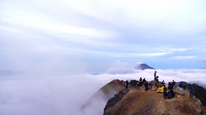 Pengunjung menikmati pemandangan di puncak Gunung Sibayak.