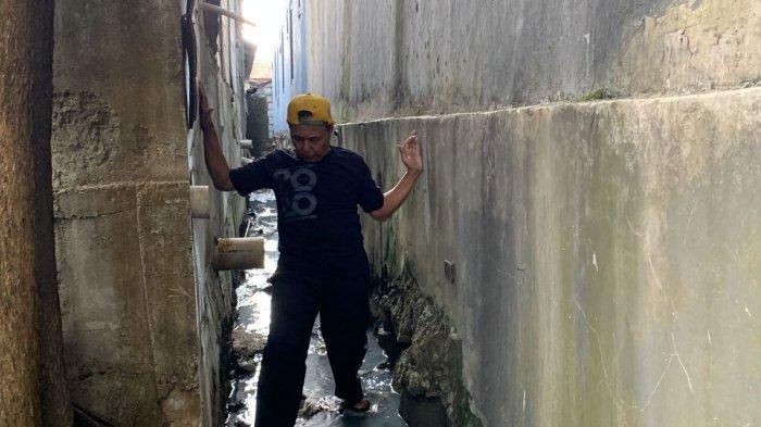 JALAN KELUAR MASUK RUMAH DITUTUP TEMBOK - Rumah Ngadenin (63) di Jalan Raya Jatiwaringin, RT 03 RW 04, Kecamatan Pondok Gede, Kota Bekasi, yang akses keluar masuk rumah telah ditutup tembok hotel setinggi 15 meter. Pada Minggu (9/7/2023), Ngadenin menunjukkan tingginya tembok hotel yang menutupi depan, belakang dan samping rumahnya. (KOMPAS.com/FIRDA JANATI)