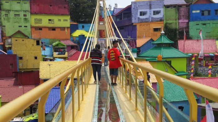 Sejumlah wisatawan saat melintas di jembatan kaca yang menghubungkan Kampung Warna - warni dan Kampung Tridi di Kota Malang, Jawa Timur, Selasa (10/10/2017)(KOMPAS.com / Andi Hartik)