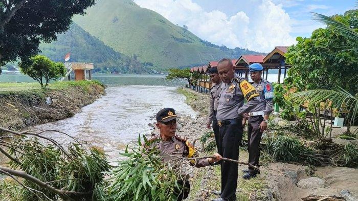 Personel Polres Tanah Karo membantu meringankan beban warga dengan membersihkan pepohonan yang tumbang di perladangan warga akibat banjir Sungai Sidoppak meluap ke Desa Tongging, Dusun II Kecamatan Merek Kabupaten Karo, Rabu (24/1/202.)