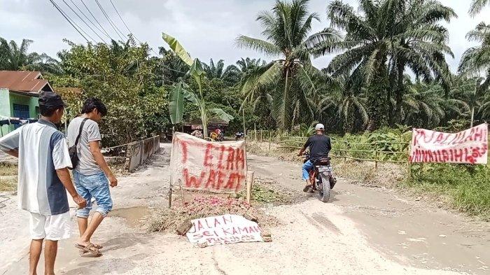 Warga bangun kuburan di tengah jalan rusak sebagai bentuk protes kepada Pemkab Asahan yang terkesan tutup mata selama bertahun-tahun.(Alif Alqadri Harahap / Tribun-Medan.com)