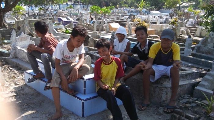 Libur sekolah dimanfaatkan anak-anak untuk mengais rezeki dari para peziarah di TPU Jalinsum dekat Kantor DPRD Deliserdang, Senin (23/6/2014)