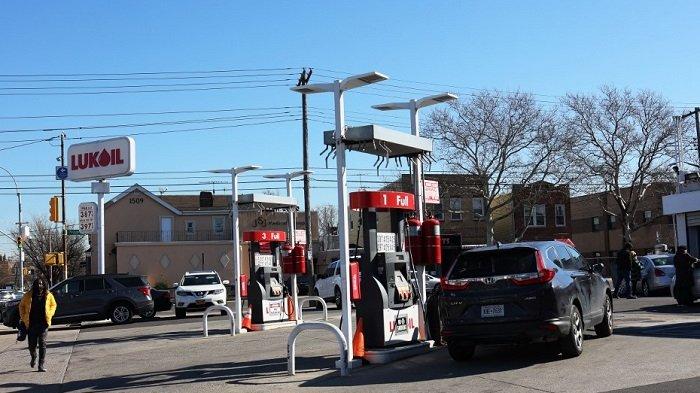 Warga berjalan melewati pompa bensin Lukoil di lingkungan Canarsie di Brooklyn di New York City, Jumat (4/3/2022).