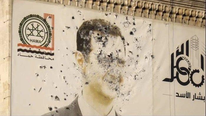 Foto Presiden Suriah Bashar Al-Assad tampak penuh lubang peluru di sebuah kantor pemerintah Suriah usai serangan pemberontak di Hama, Jumat (6/12/2024).