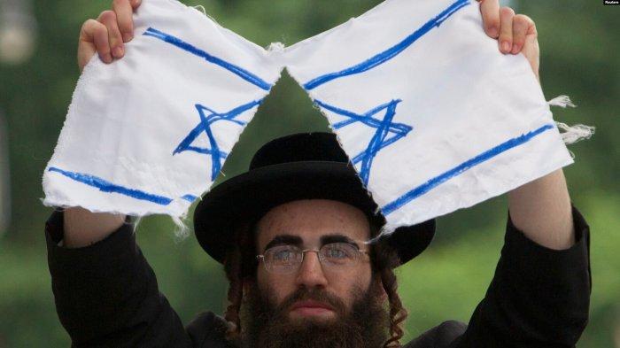 Seorang Yahudi Ortodoks anti-Zionis menyobek bendera Israel dalam protes melawan negara Israel di New York.