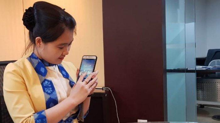 Customer Service BCA KCU Medan, Pretty menunjukkan Sakuku pada ponselnya di Bank BCA Jalan Diponegoro, Medan, Kamis (9/5/2019).