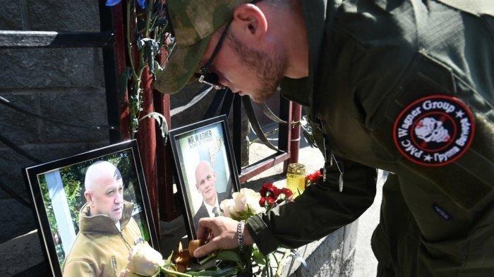 Seorang anggota kelompok tentara bayaran swasta Wagner memberikan penghormatan kepada Yevgeny Prigozhin (kiri) dan Dmitry Utkin, sosok bayangan yang mengelola operasi Wagner dan diduga bertugas di intelijen militer Rusia, di peringatan darurat di depan kantor PMC Wagner di Novosibirsk, pada bulan Agustus 24 Agustus 2023. (VLADIMIR NIKOLAYEV / AFP)