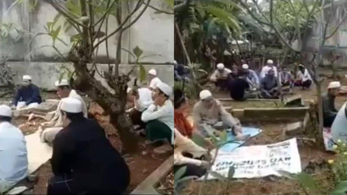 Beberapa pria sedang duduk di area sebuah pemakaman.