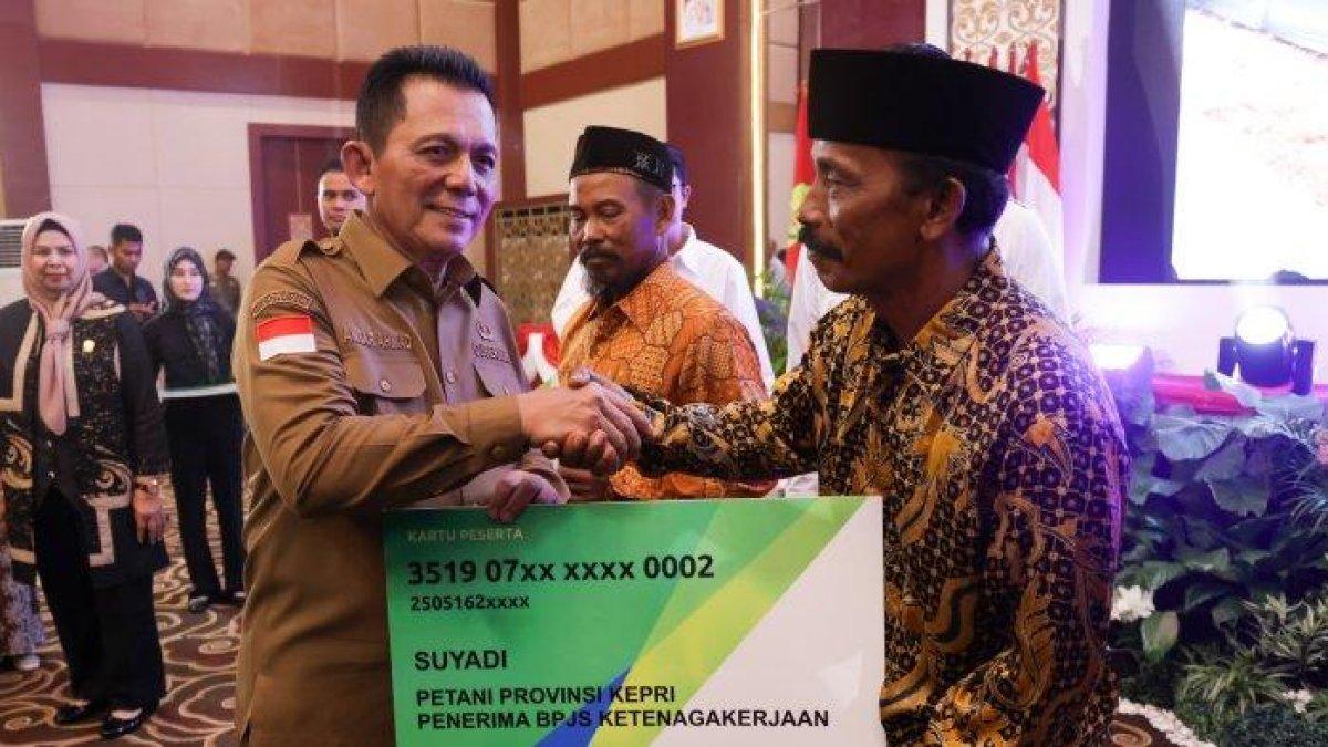 100 HARI KERJA - Gubernur Kepri, Ansar Ahmad secara simbolis menyerahkan bantuan BPJS Ketenagakerjaan bagi nelayan dan petani di Aula Wan Seri Beni, Dompak, Tanjungpinang, Selasa (27/5/2025).