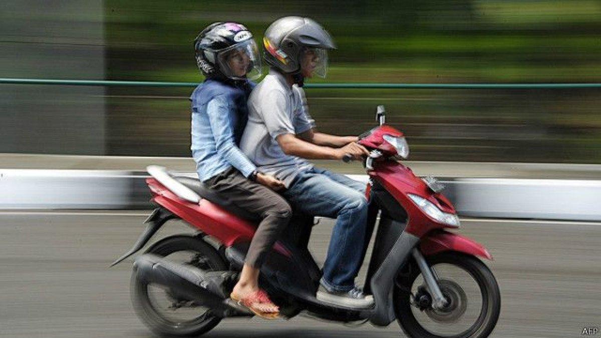 Ilustrasi suami istri boncengan menunggangi sepeda motor.