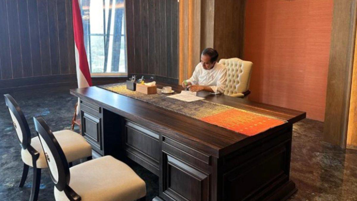 Jokowi sedang bekerja di ruang kerja presiden ditemani secangkir minuman