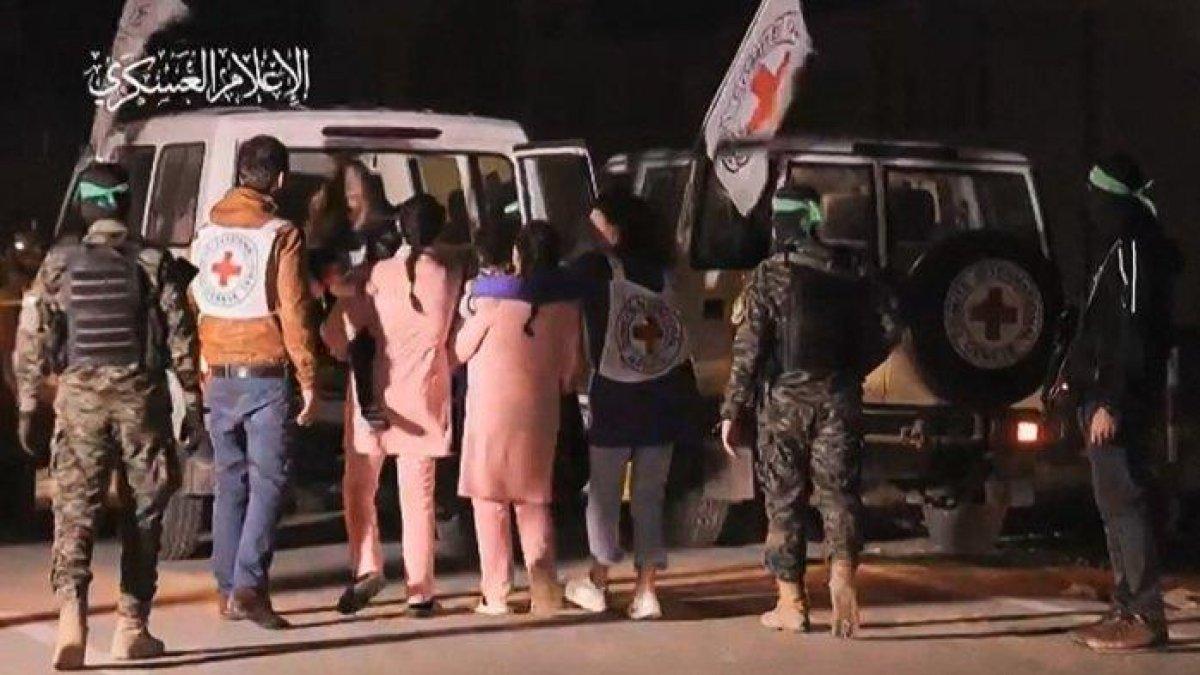 Pengambilan gambar dari video selebaran yang dirilis oleh Kantor Media Hamas menunjukkan pejuang Hamas menemani sandera Israel yang baru dibebaskan (berbaju merah muda) ke kendaraan Palang Merah, di Jalur Gaza pada 27 November 2023. Militer Israel mengatakan pada 27 November 2023 bahwa 11 sandera yang dibebaskan di Jalur Gaza telah kembali ke wilayah Israel.