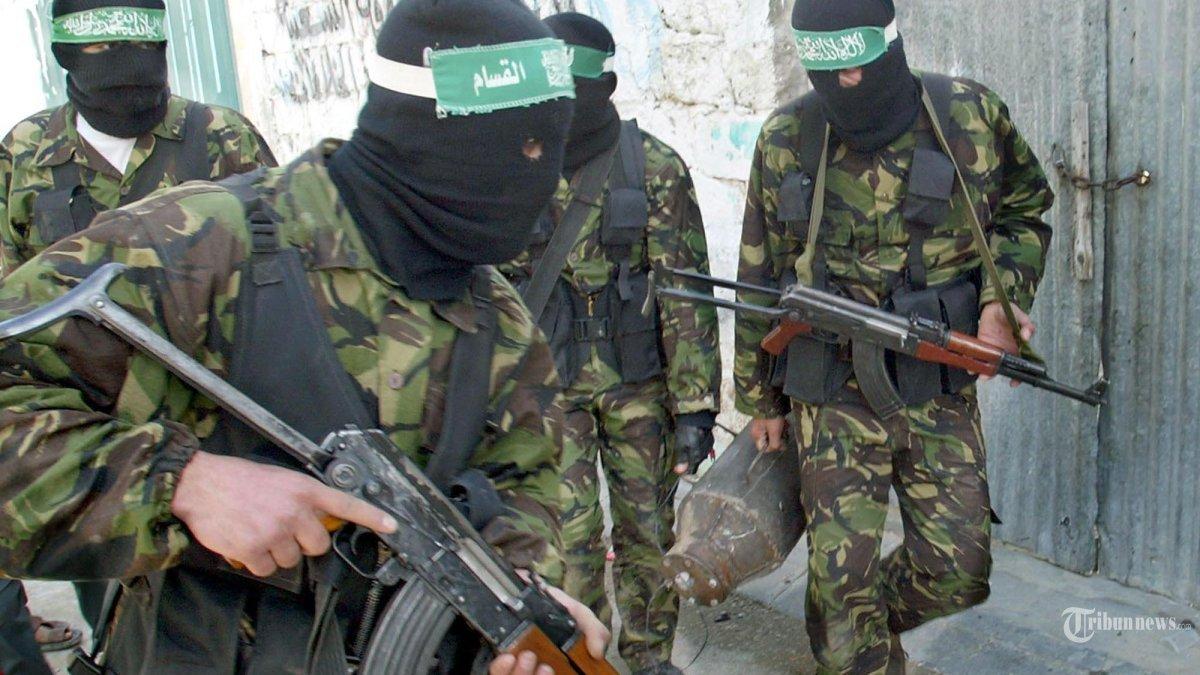 Militan Palestina dari Brigade Ezzeddine al-Qassam, sayap militer kelompok Islam militan Hamas, membawa bom (kanan) saat mereka berjalan bersenjata di sepanjang jalan di Beit Hanun di Jalur Gaza utara