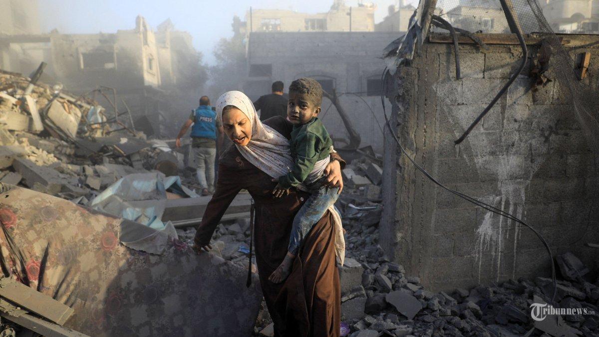 Orang-orang melarikan diri setelah serangan udara Israel di lingkungan kamp pengungsi al-Maghazi di Jalur Gaza tengah pada 6 November 2023, di tengah pertempuran yang sedang berlangsung antara Israel dan gerakan Hamas Palestina. Ribuan warga sipil, baik warga Palestina maupun Israel, telah tewas sejak 7 Oktober 2023, setelah militan Hamas Palestina yang berbasis di Jalur Gaza memasuki Israel selatan dalam serangan yang belum pernah terjadi sebelumnya yang memicu perang yang diumumkan oleh Israel terhadap Hamas dengan pemboman balasan di Gaza.