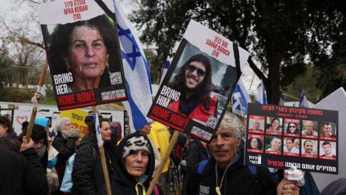 Para pengunjuk rasa mengangkat plakat dan bendera nasional selama unjuk rasa menuntut pembebasan warga Israel yang disandera seratus hari sebelumnya oleh kelompok Hamas Palestina pada 7 Oktober, di luar Parlemen Israel di Yerusalem pada 15 Januari 2024.