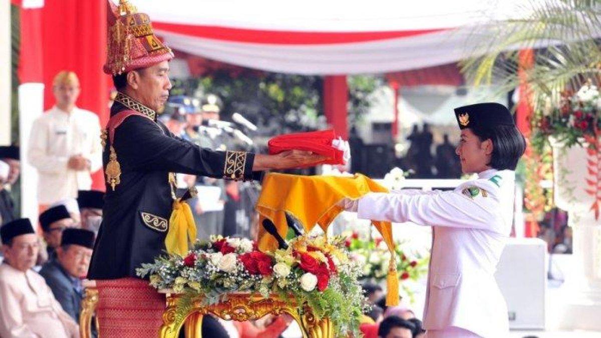 Presiden Jokowi menyerahkan bendera kepada Tim Paskibraka, di halaman Istana Merdeka, Jakarta, Jumat (18/9/2018).