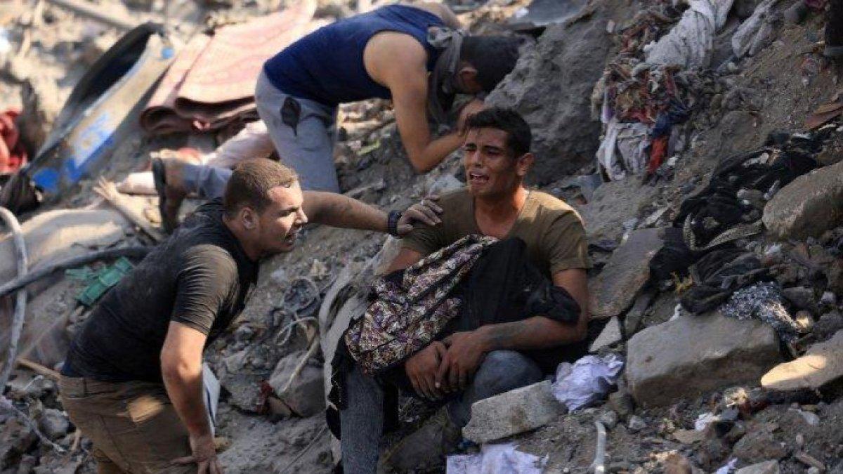 Pria bereaksi sambil menggendong jenazah ibunya yang terbungkus selimut di Gaza