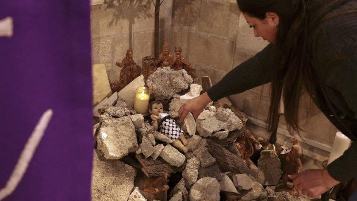 Seorang perempuan mengatur instalasi adegan kelahiran Kristus dengan figur yang melambangkan bayi Yesus yang berbaring di palungan di tengah reruntuhan, mengacu pada Gaza, di dalam Gereja Lutheran Evangelis di Betlehem di Tepi Barat yang diduduki pada tanggal 6 Desember 2023. Itu dilakukan beberapa minggu sebelum Natal di tengah pertempuran yang terus berlanjut antara Israel dan kelompok militan Palestina, Hamas.