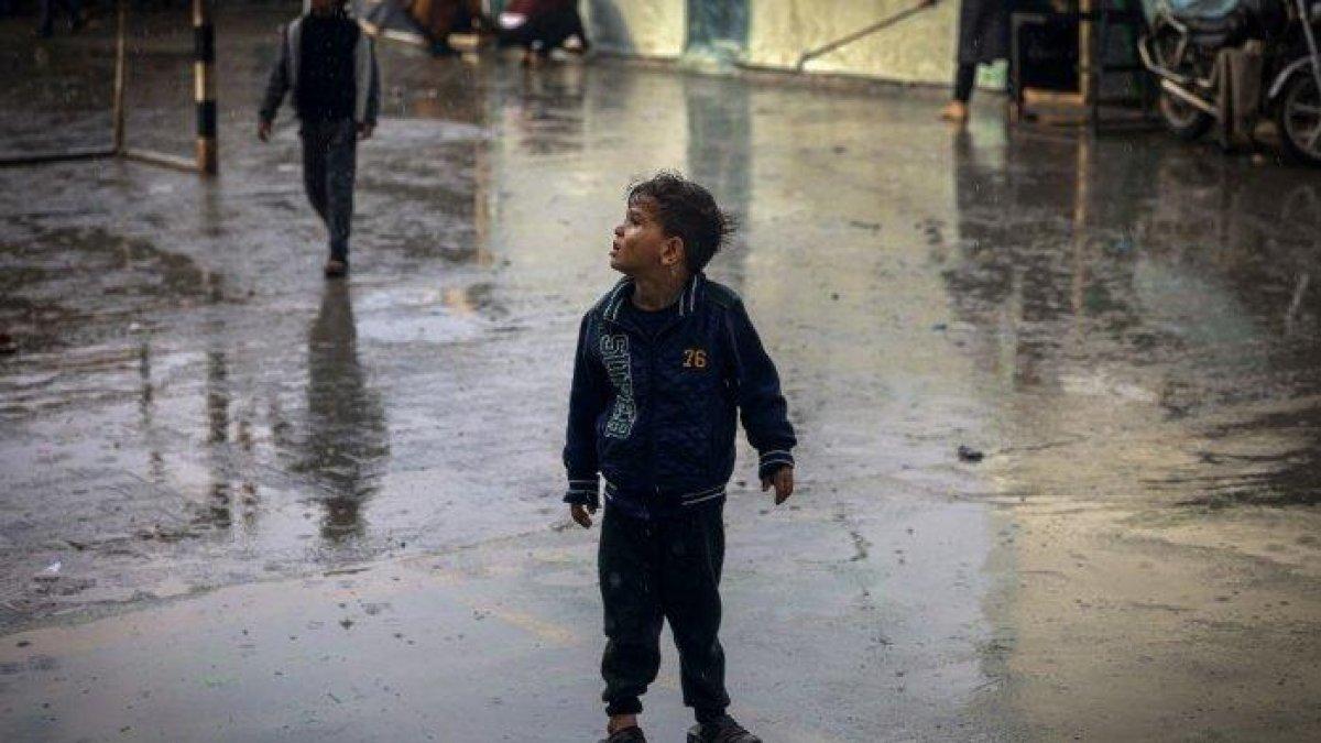 Seorang anak Palestina berjalan di tengah hujan di kamp pengungsi di Rafah, di Jalur Gaza selatan, tempat sebagian besar warga sipil berlindung saat pertempuran berlanjut antara Israel dan kelompok militan Palestina Hamas, pada 12 Desember 2023.