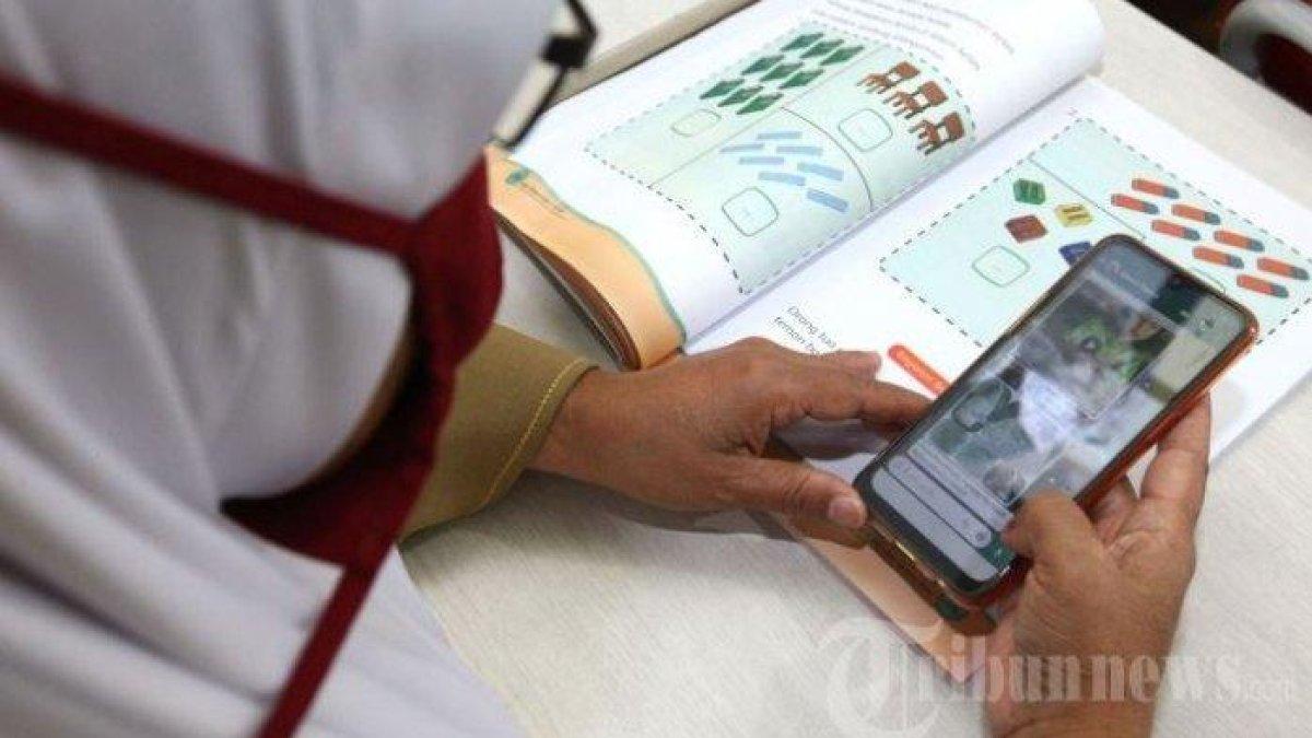 Seorang guru kelas melakukan kegiatan mengajar jarak jauh kepada peserta didik.