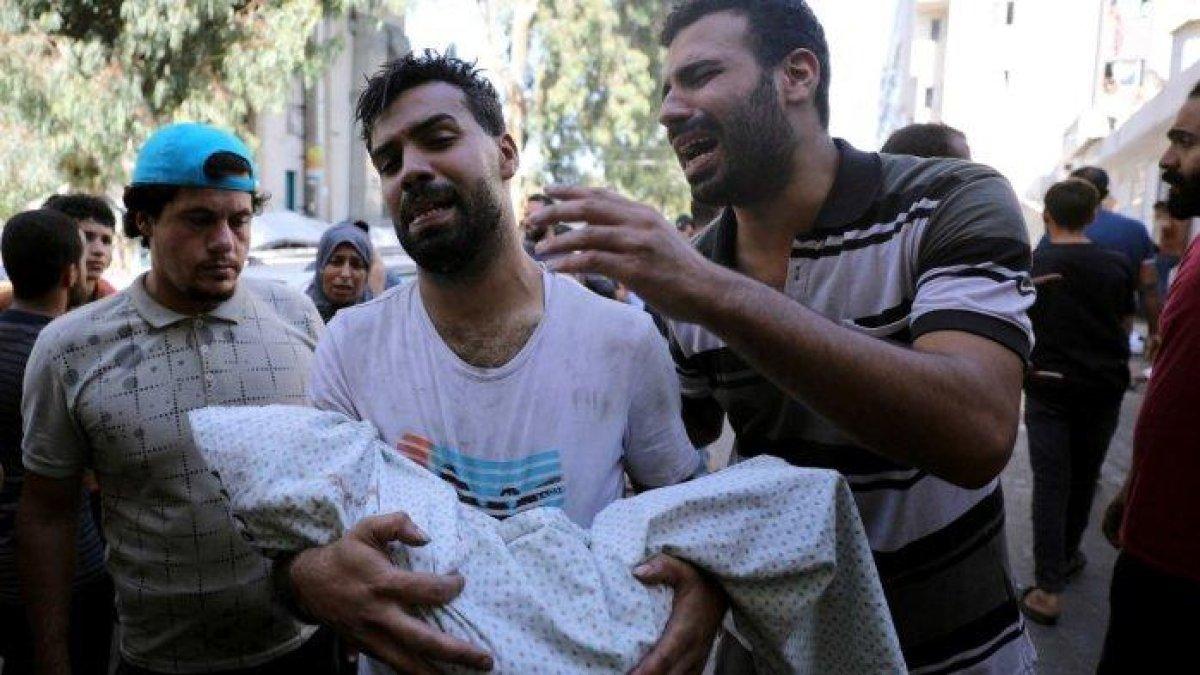 Seorang warga Palestina memegang jenazah seorang anak yang terbungkus kain kafan sementara orang lain bereaksi di sampingnya, di luar rumah sakit setelah pemboman Israel di pinggiran timur Kota Gaza, Shujaiya pada 4 November 2023, di tengah pertempuran yang sedang berlangsung antara Israel dan kelompok Palestina Hamas.