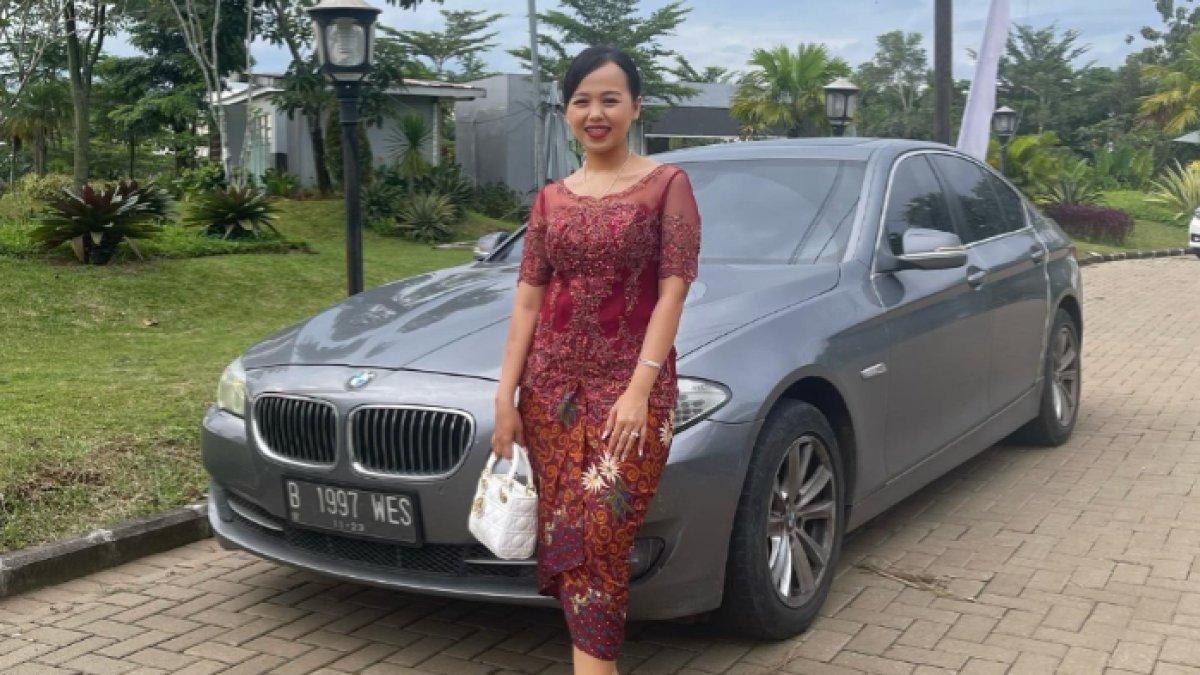 Tri Wahyuni saat berpose di depan mobil.