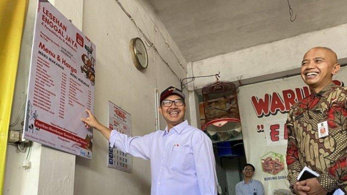 100 HARI KERJA - Wali Kota Yogyakarta, Hasto Wardoyo, menunjukkan papan daftar menu dan harga yang dipasang di salah satu warung di Jalan Perwakilan, kawasan Malioboro, Kota Yogyakarta, Selasa (25/3/2025).