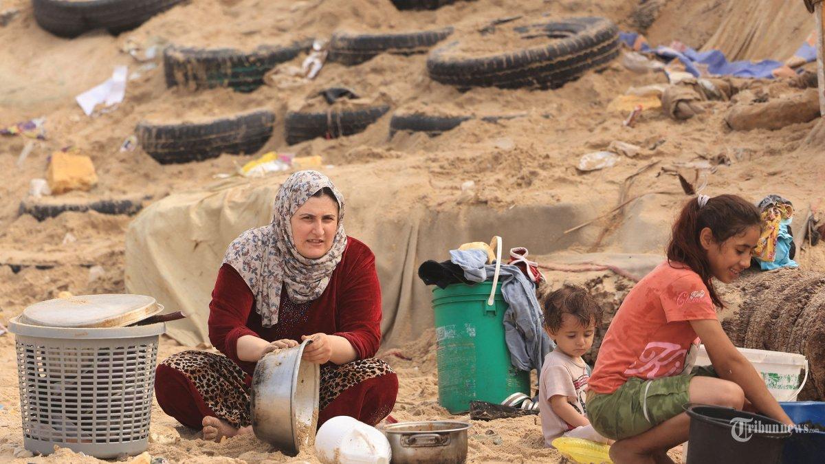 Seorang wanita Palestina membersihkan panci masaknya menggunakan air laut karena kekurangan air bersih dan listrik, di sepanjang pantai di Deir el-Balah di Jalur Gaza selatan pada 29 Oktober 2023, di tengah pertempuran yang sedang berlangsung antara Israel dan kelompok Palestina Hamas . Israel menggempur Gaza yang dikuasai Hamas pada tanggal 29 Oktober, dalam serangan udara dan darat yang meningkat ketika PBB memperingatkan bahwa ketertiban sipil ?mulai rusak? di wilayah Palestina yang terkepung. Ribuan warga sipil, baik warga Palestina maupun Israel, telah tewas sejak 7 Oktober 2023, setelah militan Hamas Palestina yang berbasis di Jalur Gaza memasuki Israel selatan dalam serangan yang belum pernah terjadi sebelumnya yang memicu perang yang diumumkan oleh Israel terhadap Hamas dengan pemboman balasan di Gaza.