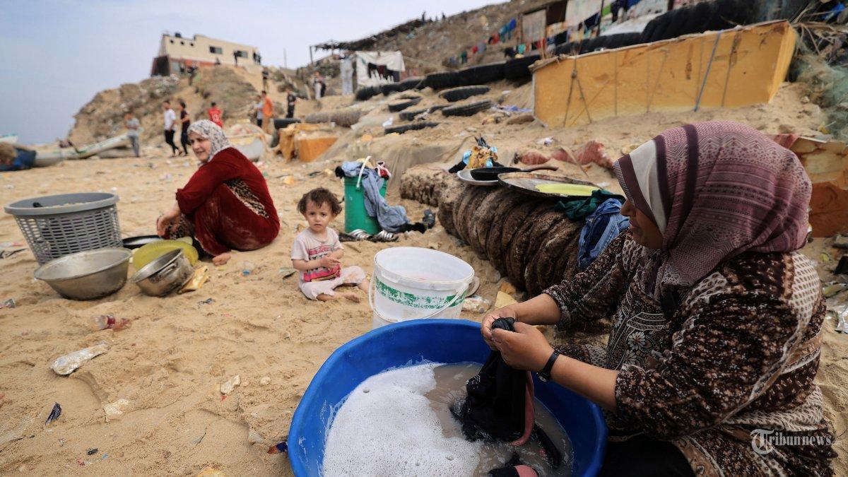 Wanita Palestina mencuci pakaian mereka menggunakan air laut karena kurangnya air bersih dan listrik, di sepanjang pantai di Deir el-Balah di selatan Jalur Gaza pada 29 Oktober 2023, di tengah pertempuran yang sedang berlangsung antara Israel dan kelompok Palestina Hamas.