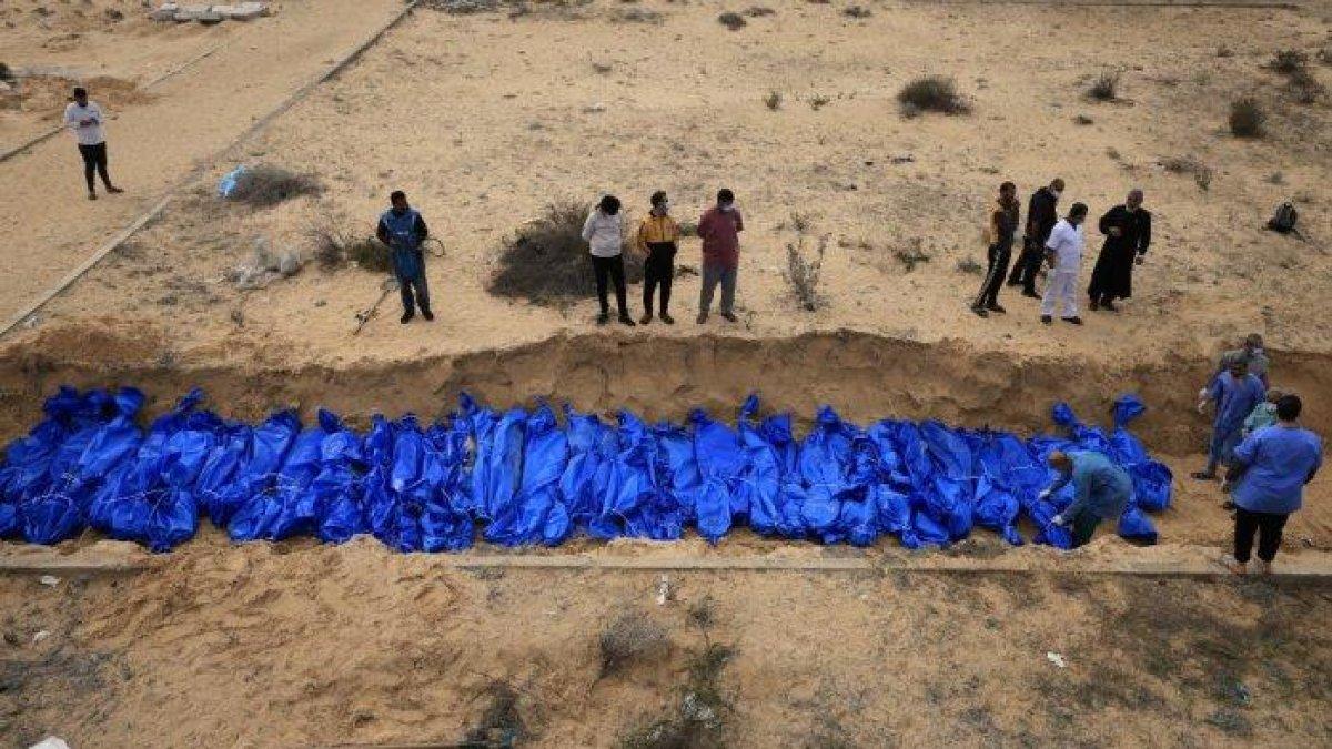 Warga Palestina menguburkan jenazah di kuburan massal di pemakaman Khan Yunis, di Jalur Gaza selatan pada 22 November 2023, di tengah pertempuran yang sedang berlangsung antara Israel dan gerakan Hamas Palestina. Jenazah tersebut, yang hanya diidentifikasi dengan angka, berasal dari rumah sakit Al-Shifa dan Beit Hanoun di Jalur Gaza utara, menurut anggota komite di lokasi pemakaman.