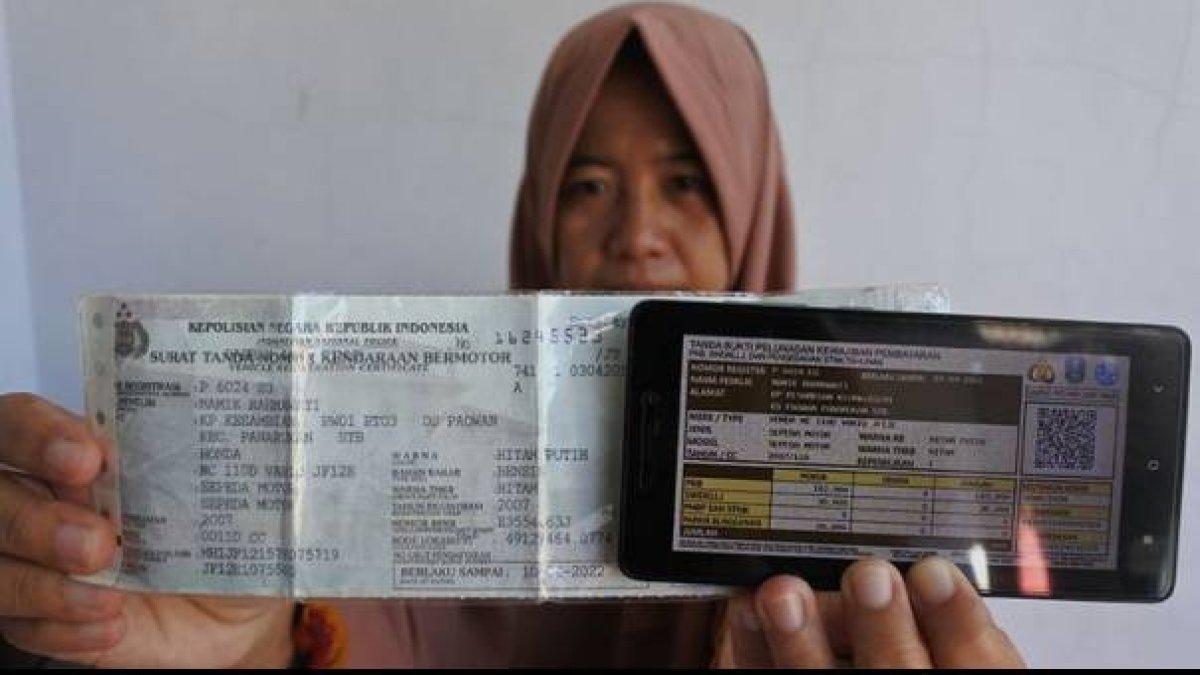 Warga menunjukkan bukti pelunasan pajak kendaraan bermotor lewat STNK yang dibayarkan secara online.