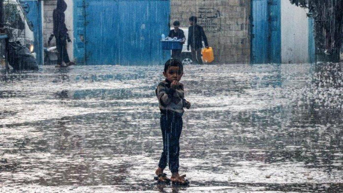 Seorang anak laki-laki berdiri di tengah hujan di sebuah sekolah yang dikelola oleh Badan Bantuan dan Pekerjaan PBB untuk Pengungsi Palestina di Jalur Gaza selatan pada 14 November 2023.