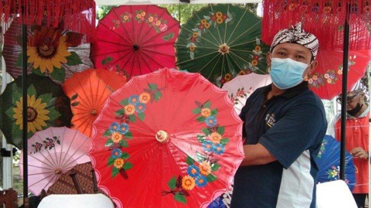 KERAJINAN KHAS KLATEN - Seorang penjaga stand saat menunjukkan payung hias Juwiring saat mengikuti UMKM Fair di Halaman Parkir Pemkab Klaten, Jumat (22/7/2022).
